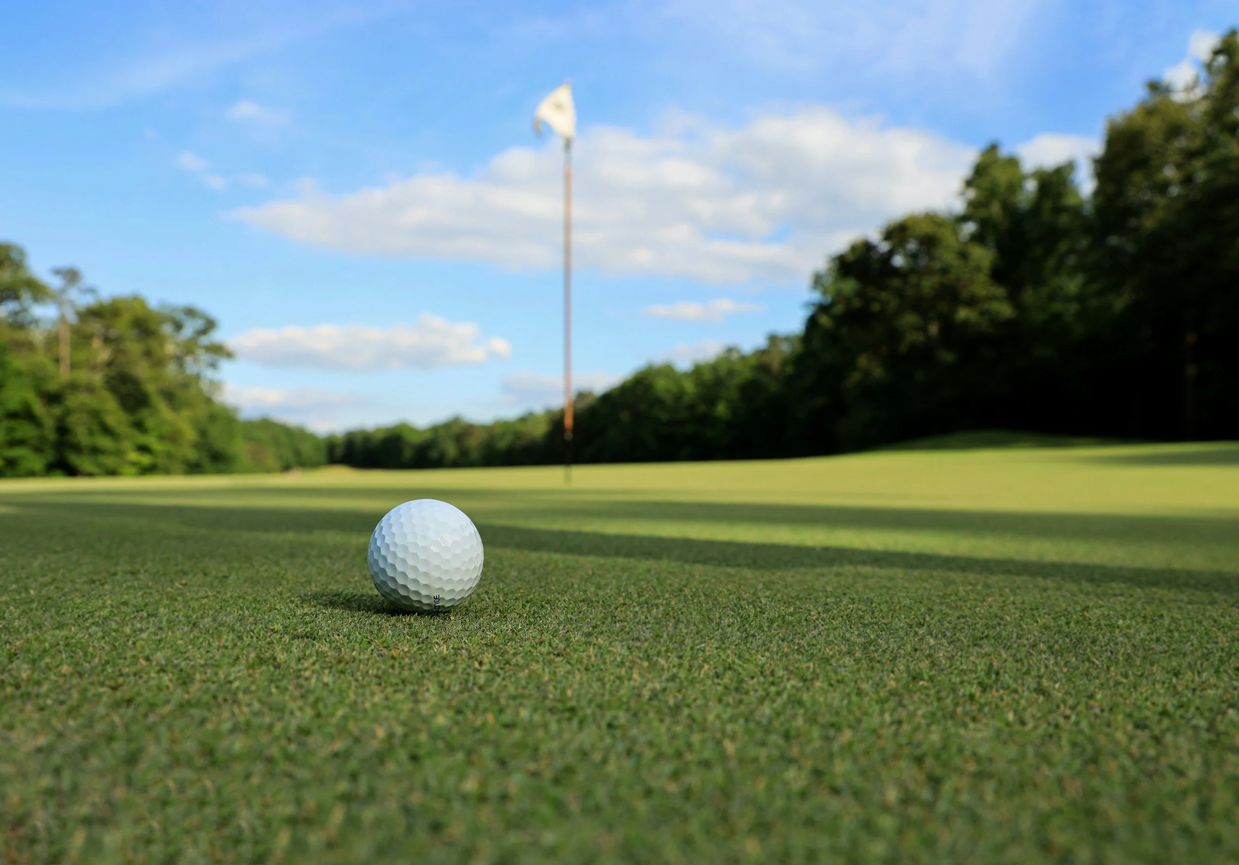 Golf ball on the green with the flag ahead